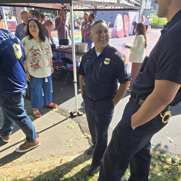 An officer speaks casually with another attendee near a Cleveland Cavaliers tent as guests mingle around the basketball court.