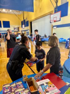 Officers and volunteers distribute folders and supplies to a young student at RG Jones School’s Family Night.