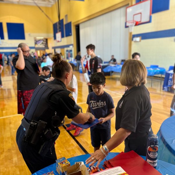 Officers and volunteers distribute folders and supplies to a young student at RG Jones School’s Family Night.