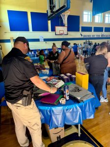 First District officer hands out school supplies to families at a table in the RG Jones School gym during Family Night.