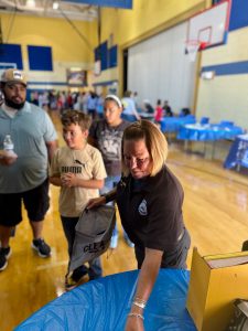 An officer hands out school supplies to children and families at a table inside the RG Jones School gym.