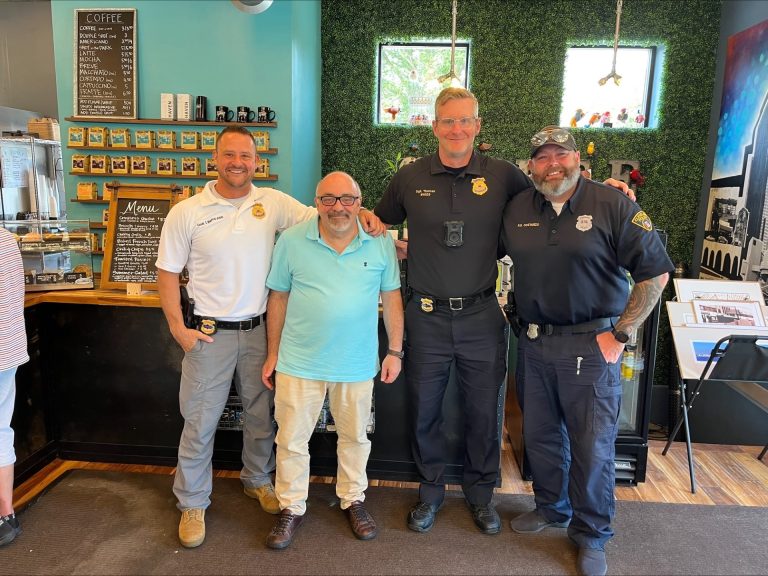 Commander Tim Maffo-Judd, Sgt. Thomas, and Officer Costanzo of the Cleveland Division of Police pose with Tremont West Community Involvement Manager Scott Rosenstein inside Metropolitan Coffee in Old Brooklyn during a community engagement visit.