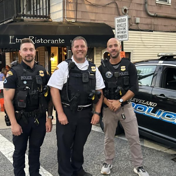 Three Cleveland Police officers stand smiling on Mayfield Road in front of Etna Ristorante during the Feast of the Assumption.