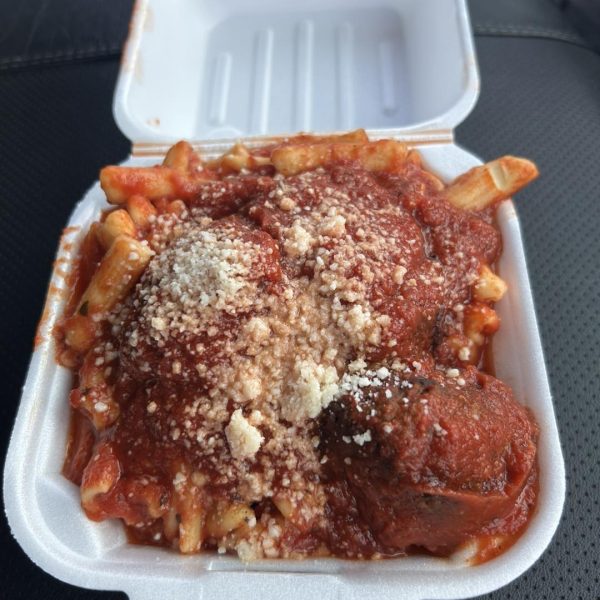 A takeout container filled with baked ziti topped with tomato sauce, meatballs, and grated cheese at the Feast of the Assumption.
