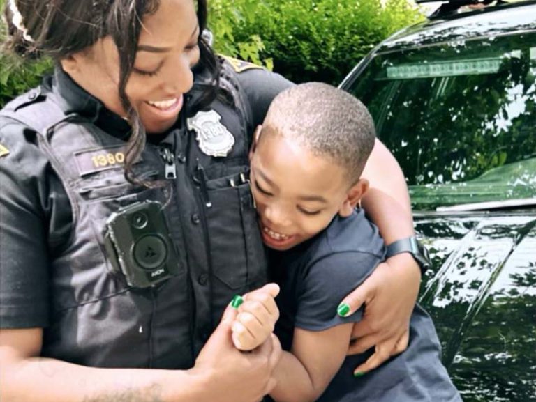 Cleveland Police Officer Vaden shares a joyful hug with her son beside a patrol vehicle.