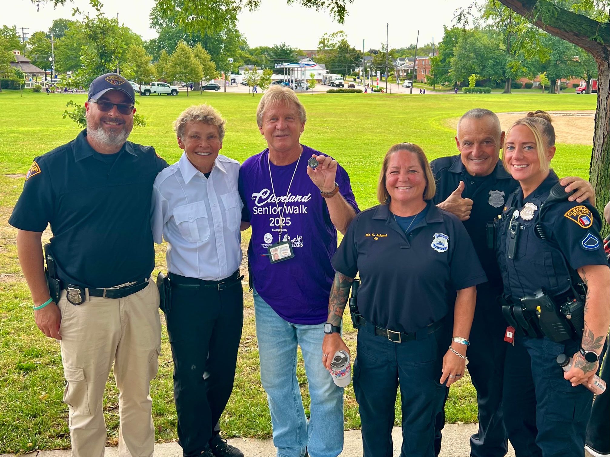 First District officers and Councilman Kelley stand together under a park tree at Halloran Park, smiling after the morning walk.
