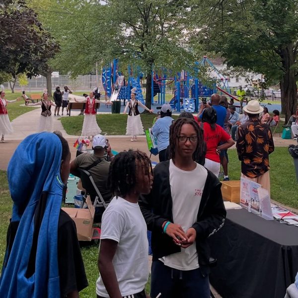 Families and children watch a group of dancers perform in traditional dress near the playground at Fairfax Recreation Center during National Night Out.