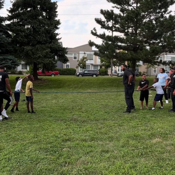 Kids, officers, and community members share the rope in a spirited tug of war game on the lawn at Fairfax Recreation Center.