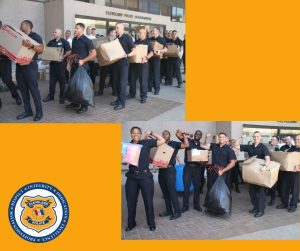 Lines of police academy recruits carry boxes and bags of donations outside Cleveland Police Headquarters, smiling and posing together with collected items.
