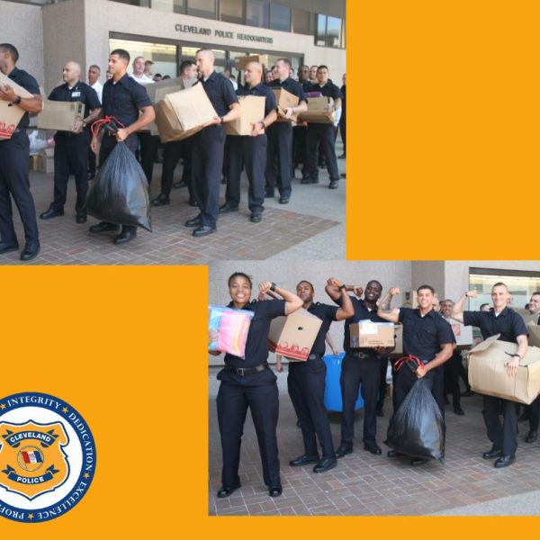 Lines of police academy recruits carry boxes and bags of donations outside Cleveland Police Headquarters, smiling and posing together with collected items.