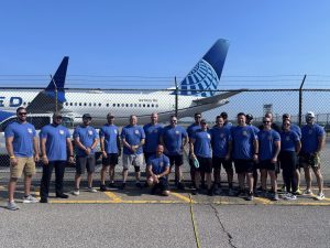 The Cleveland Police Plane Pull team poses in blue shirts in front of a United Airlines plane after competing.
