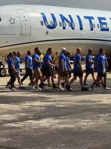 Second District officers and teammates in matching blue shirts walk past a United Airlines jet on the tarmac before their pull.