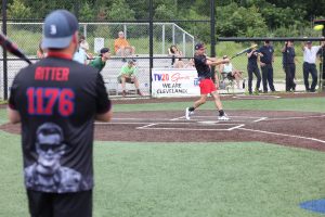 Cleveland Police softball player swings at a pitch while a teammate wearing a “Ritter 1176” jersey watches from the on-deck circle.