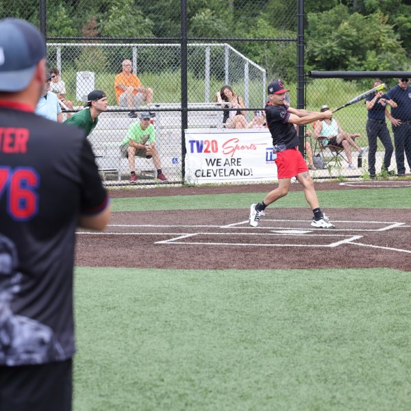Cleveland Police softball player swings at a pitch while a teammate wearing a “Ritter 1176” jersey watches from the on-deck circle.
