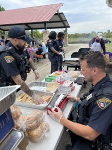 Second District officers serving hot dogs and burgers at the grill with volunteers.