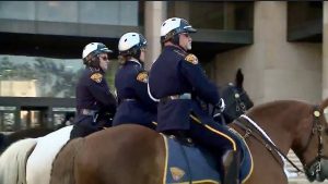 Three Cleveland Police Mounted Unit officers in uniform riding side by side through downtown.
