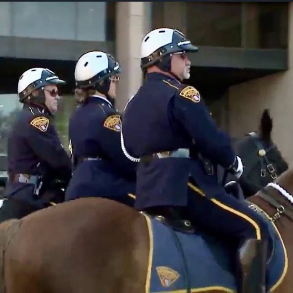 Three Cleveland Police Mounted Unit officers in uniform riding side by side through downtown.