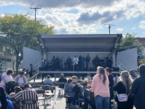 Band performing on stage while the audience gathers under partly cloudy skies.