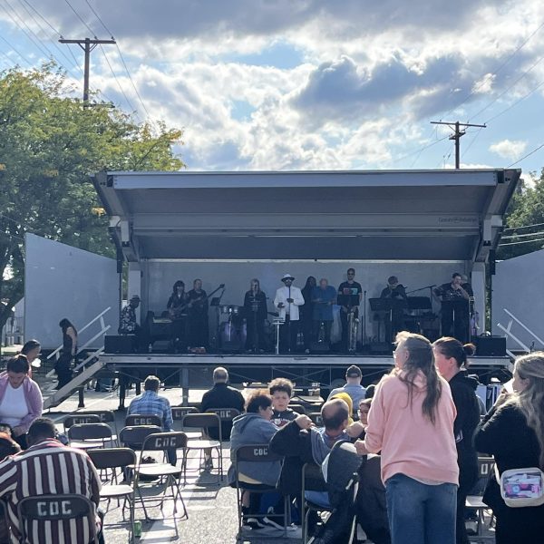 Band performing on stage while the audience gathers under partly cloudy skies.