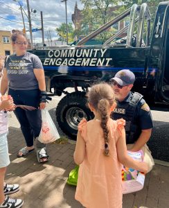 Officer handing out materials to children next to the CPD Monster Truck with “Community Engagement” painted on the side.
