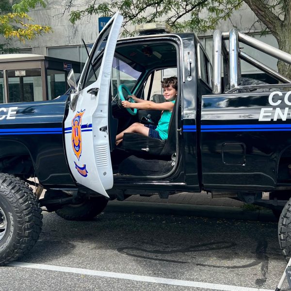 Child sitting in the driver’s seat of the restored CPD Monster Truck, smiling and holding the steering wheel.