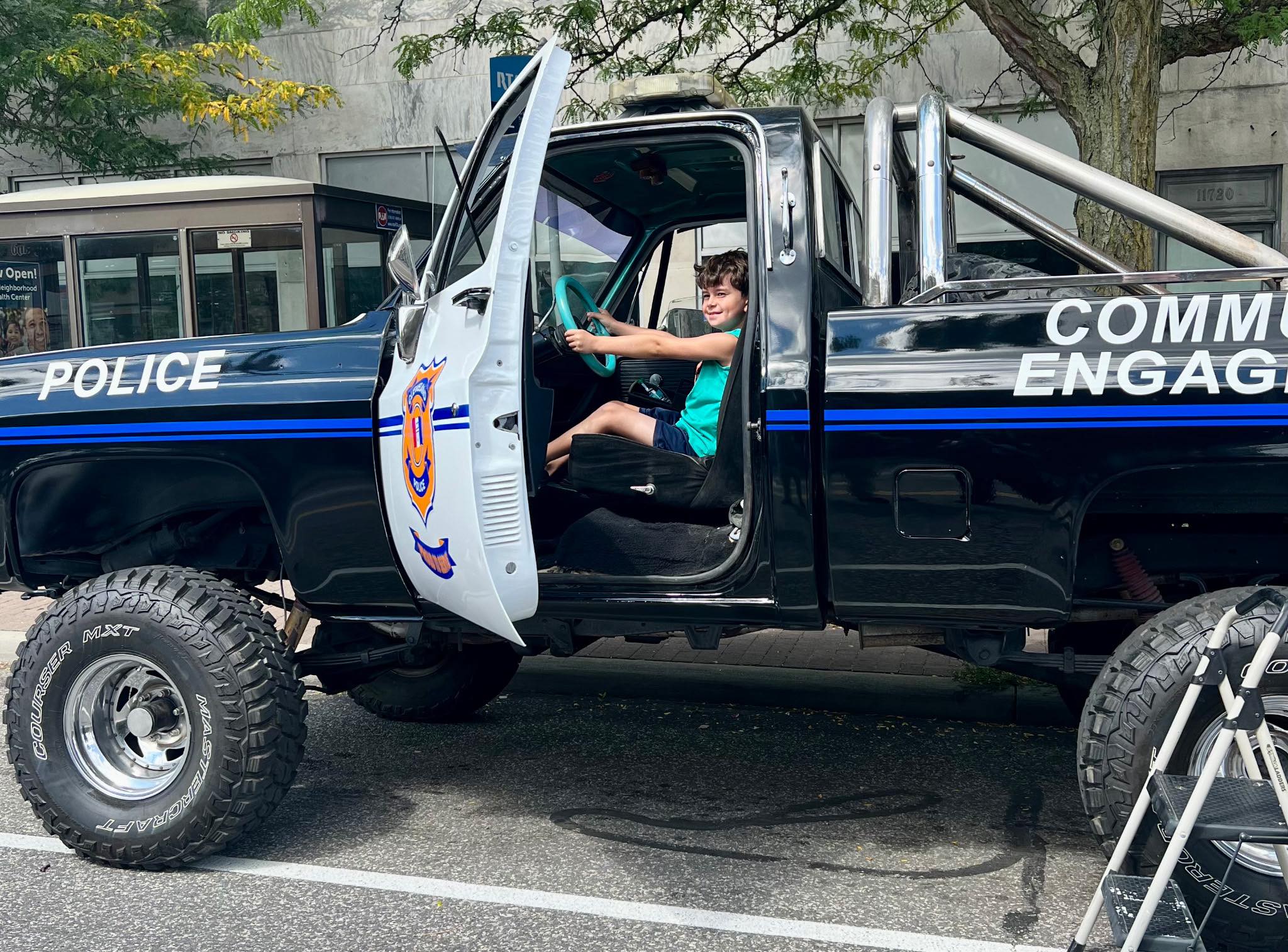 Child sitting in the driver’s seat of the restored CPD Monster Truck, smiling and holding the steering wheel.