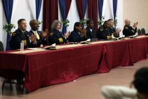 Panel of Cleveland Police officials and community leaders seated at the head table applauding.