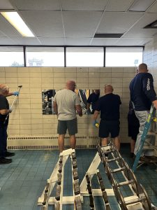 Fifth District officers and volunteers working together to clean and restore mirrors inside the gym.