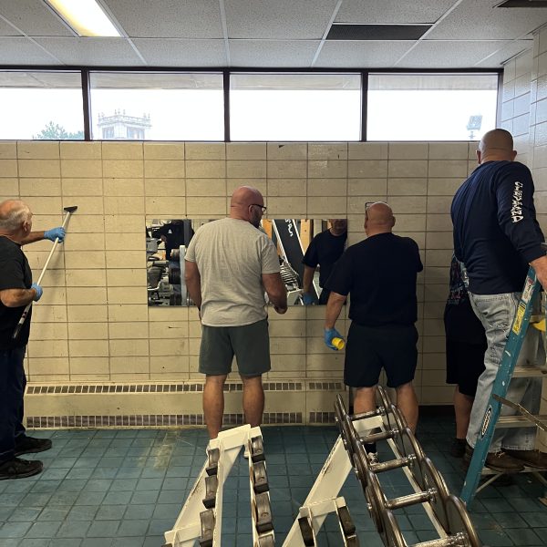 Fifth District officers and volunteers working together to clean and restore mirrors inside the gym.