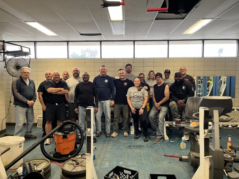 Fifth District officers, CPF supporters, and volunteers posing together inside the gym during the renovation project.