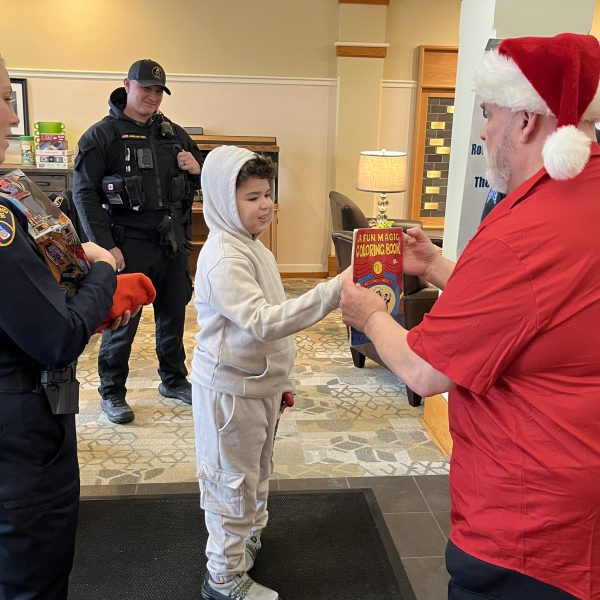 A child receives a gift from Santa Claus while Cleveland police officers look on at Ronald McDonald House.