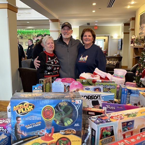 Community members stand behind a table filled with donated toys at the Cops, Kids & Christmas event.