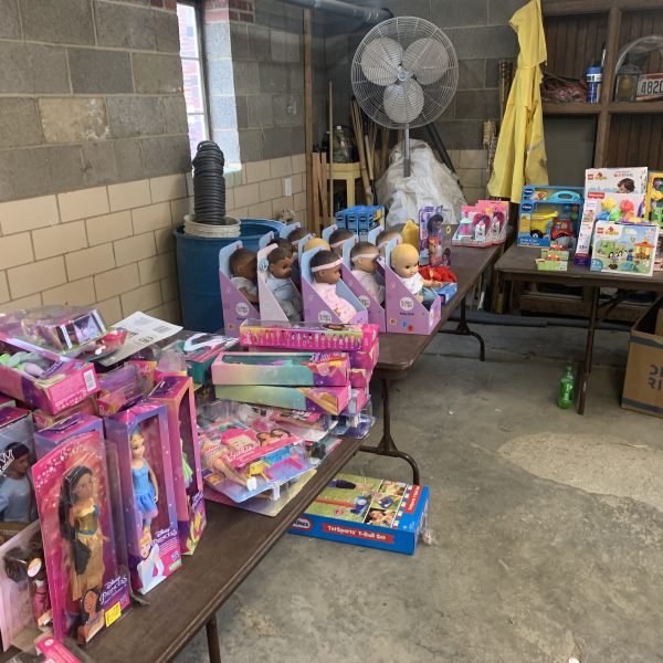 Rows of dolls and children’s toys organized on tables ahead of the Second District Christmas Drive Thru giveaway.