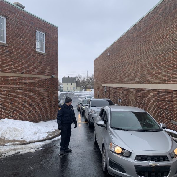 A Cleveland police officer directs vehicles through the Second District Christmas Drive Thru as families line up to receive gifts.