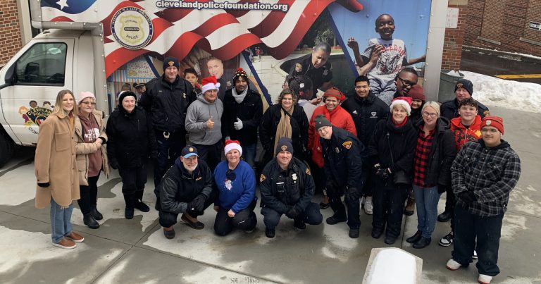 Second District officers, volunteers, and community members pose in front of the Cleveland Police Foundation outreach truck during the annual Christmas Drive Thru event.