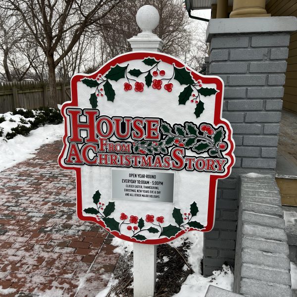 Decorative outdoor sign reading “House From A Christmas Story” with holiday-themed trim near the front walkway.