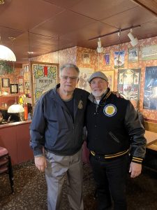 Bob Guttu standing beside Keith Sulzer inside a restaurant, posing together during a Coffee with a Cop event.