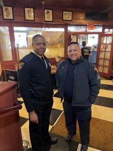 Two Cleveland police officers standing together near the restaurant entrance, smiling during a Coffee with a Cop gathering.