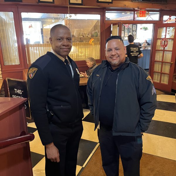 Two Cleveland police officers standing together near the restaurant entrance, smiling during a Coffee with a Cop gathering.