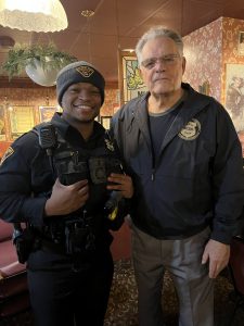 Bob Guttu standing beside a Cleveland police officer inside a restaurant, both facing the camera during a Coffee with a Cop gathering.
