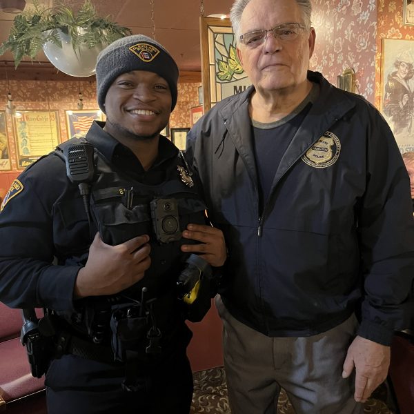Bob Guttu standing beside a Cleveland police officer inside a restaurant, both facing the camera during a Coffee with a Cop gathering.