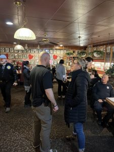 Police officers and community members standing and talking throughout a busy restaurant during a Coffee with a Cop event.