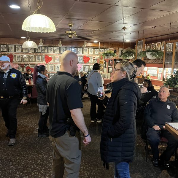 Police officers and community members standing and talking throughout a busy restaurant during a Coffee with a Cop event.