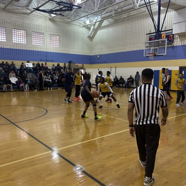 Action on the court during the Cleveland Police vs. Willson School basketball game, with a referee in the foreground