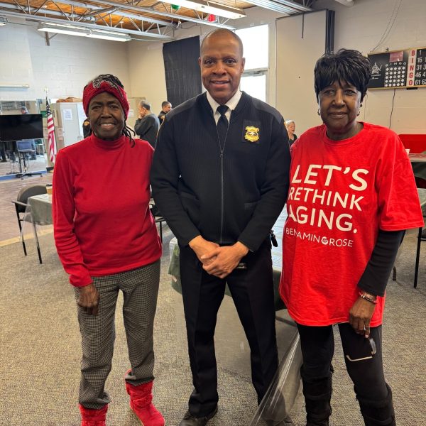 A Cleveland Police commander poses with two community members, one wearing a Benjamin Rose t-shirt, inside Gunning Recreation Center