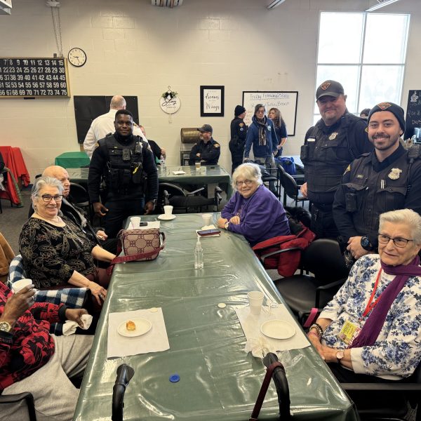 Officers and community members seated together at tables during the Coffee with a Cop event at Gunning Recreation Center