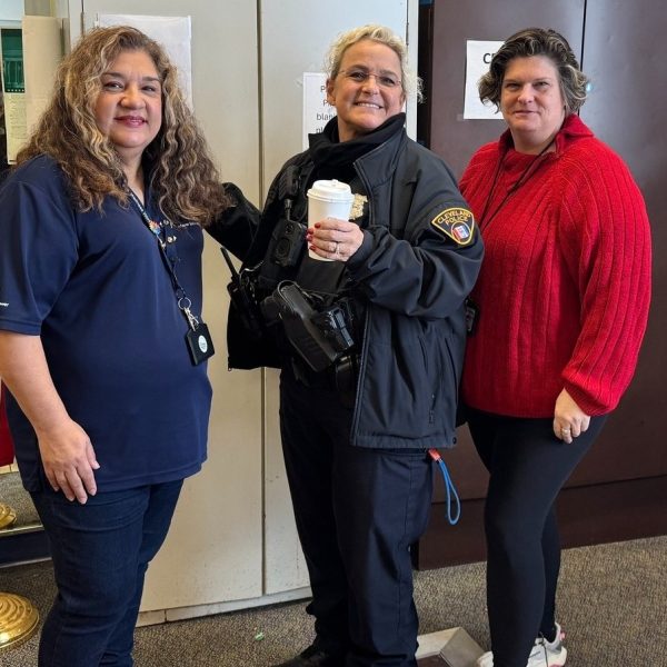 A Cleveland Police officer holds a coffee cup while posing with two staff members inside Gunning Recreation Center
