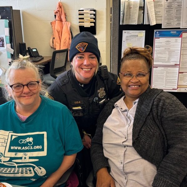 A Cleveland Police officer poses with two community members seated at a table inside Gunning Recreation Center