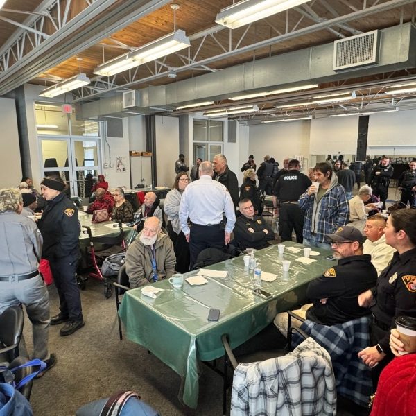 A wide view of the Coffee with a Cop event at Gunning Recreation Center, with officers and community members gathered at tables throughout the room