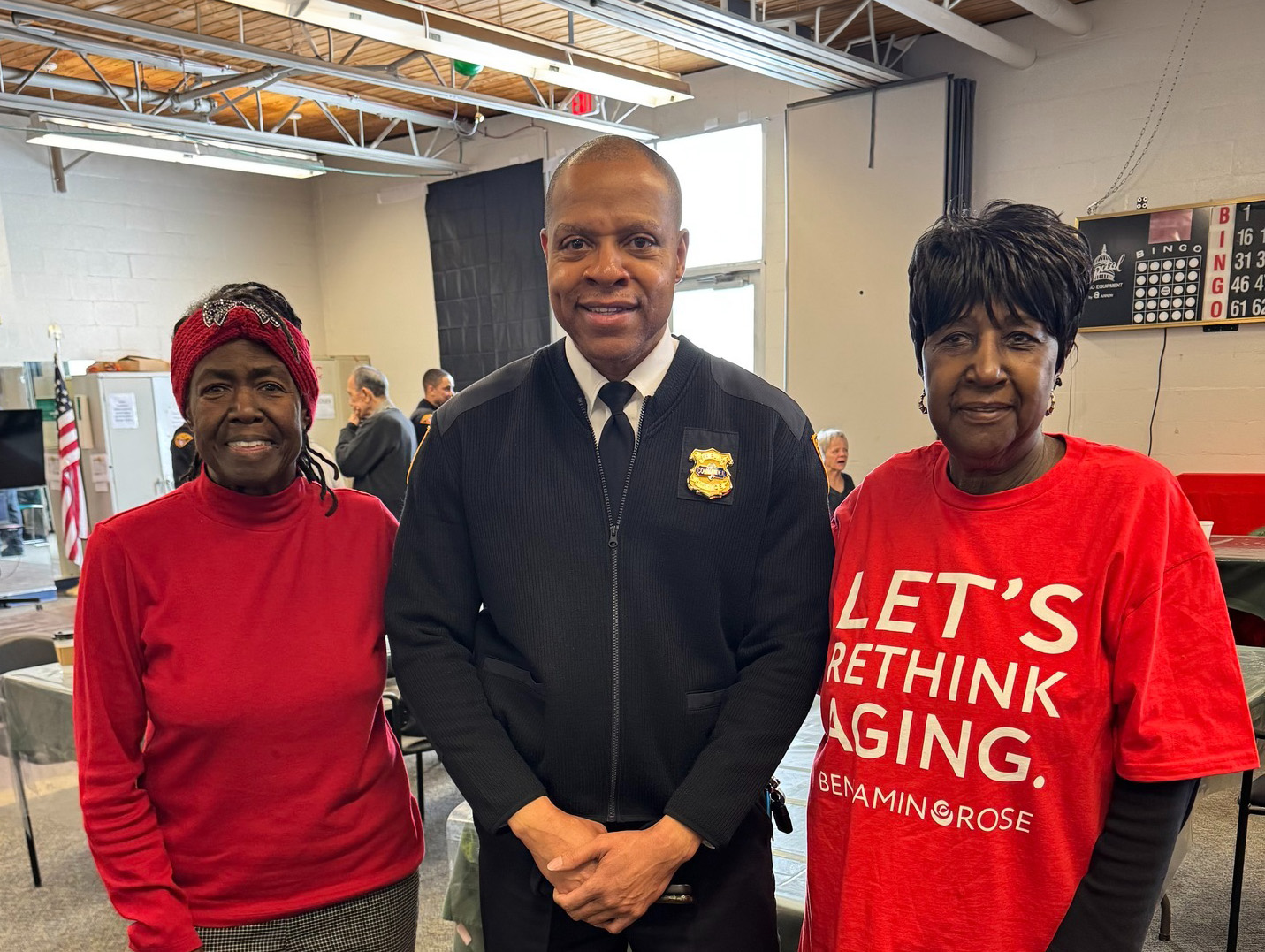 A Cleveland Police commander poses with two community members, one wearing a Benjamin Rose t-shirt, inside Gunning Recreation Center